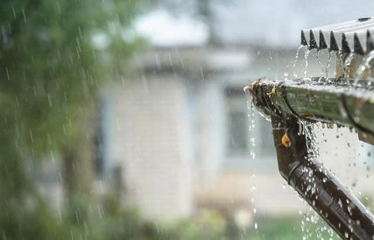 Gouttière débordant sous une forte pluie sur une maison
