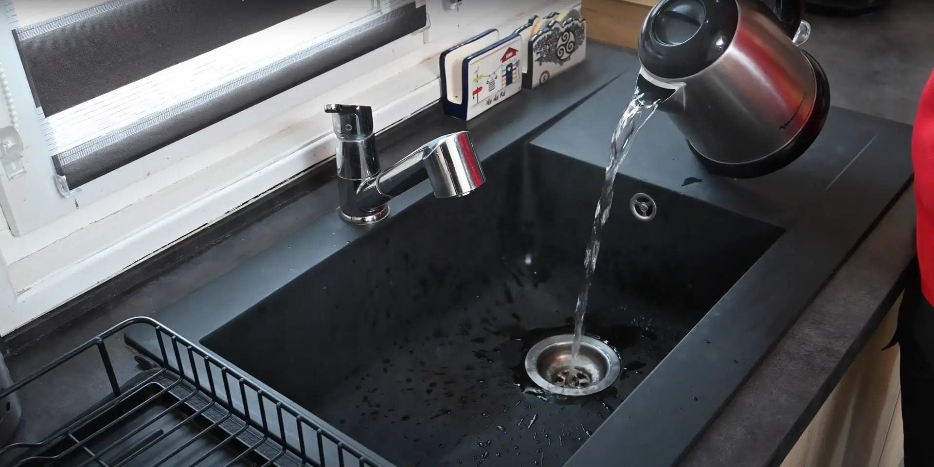 Évier de cuisine noir avec bouilloire versant de l'eau
