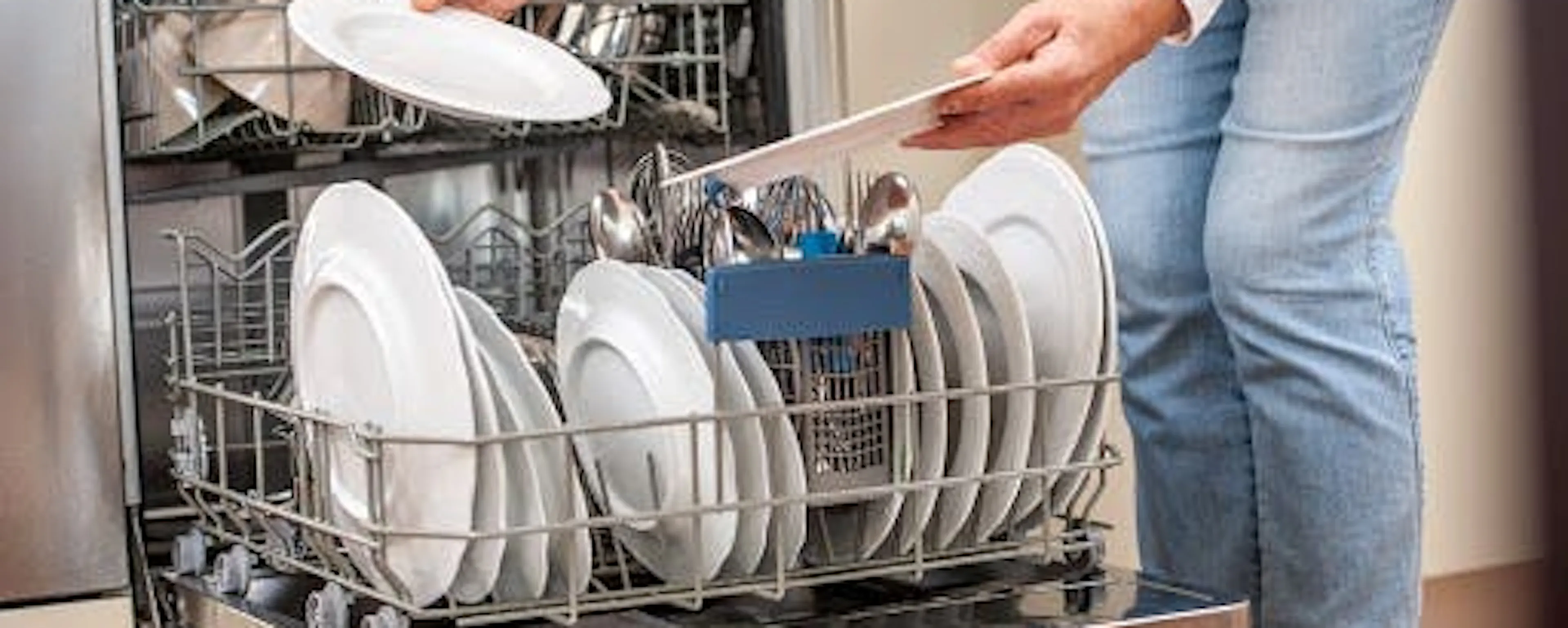 Femme chargeant un lave-vaisselle ouvert dégageant de mauvaises odeurs