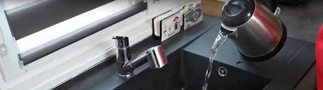 Évier de cuisine noir avec bouilloire versant de l'eau