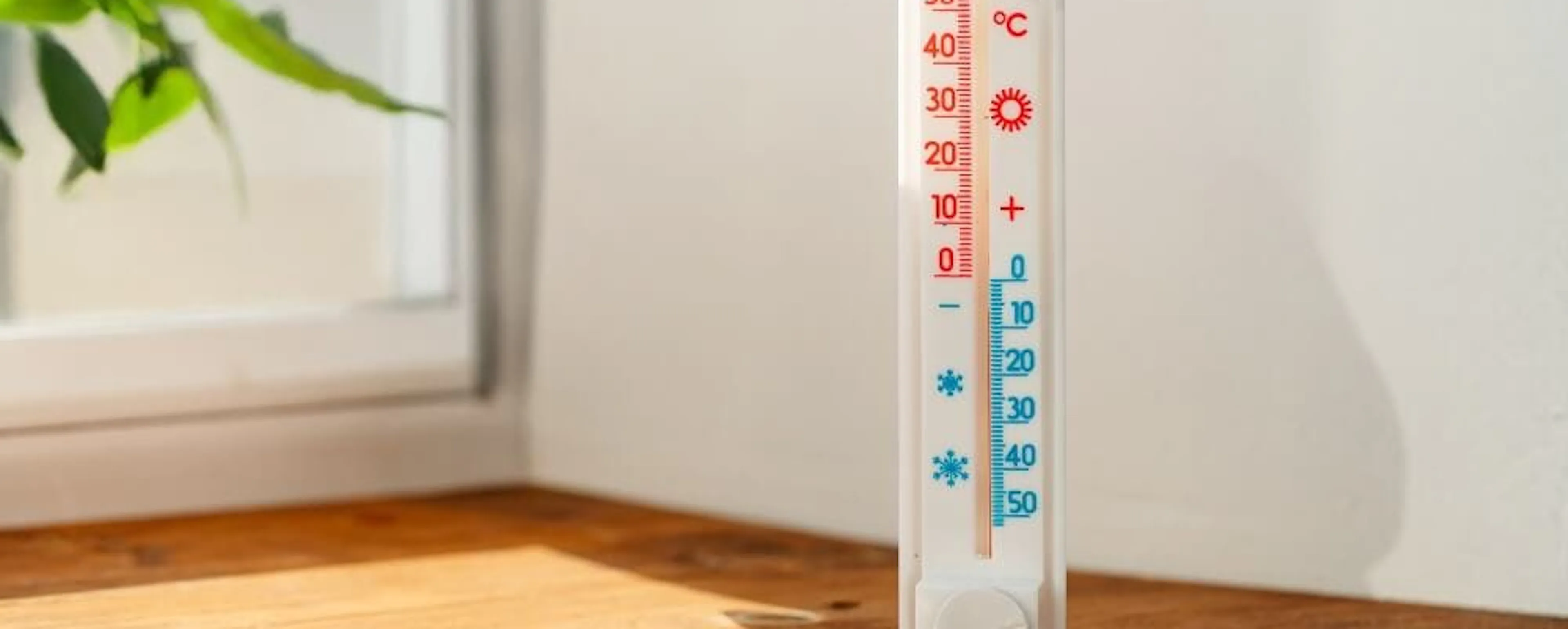 Thermomètre mural sur un rebord en bois près d'une fenêtre aidant à optimiser la capacité de chauffage