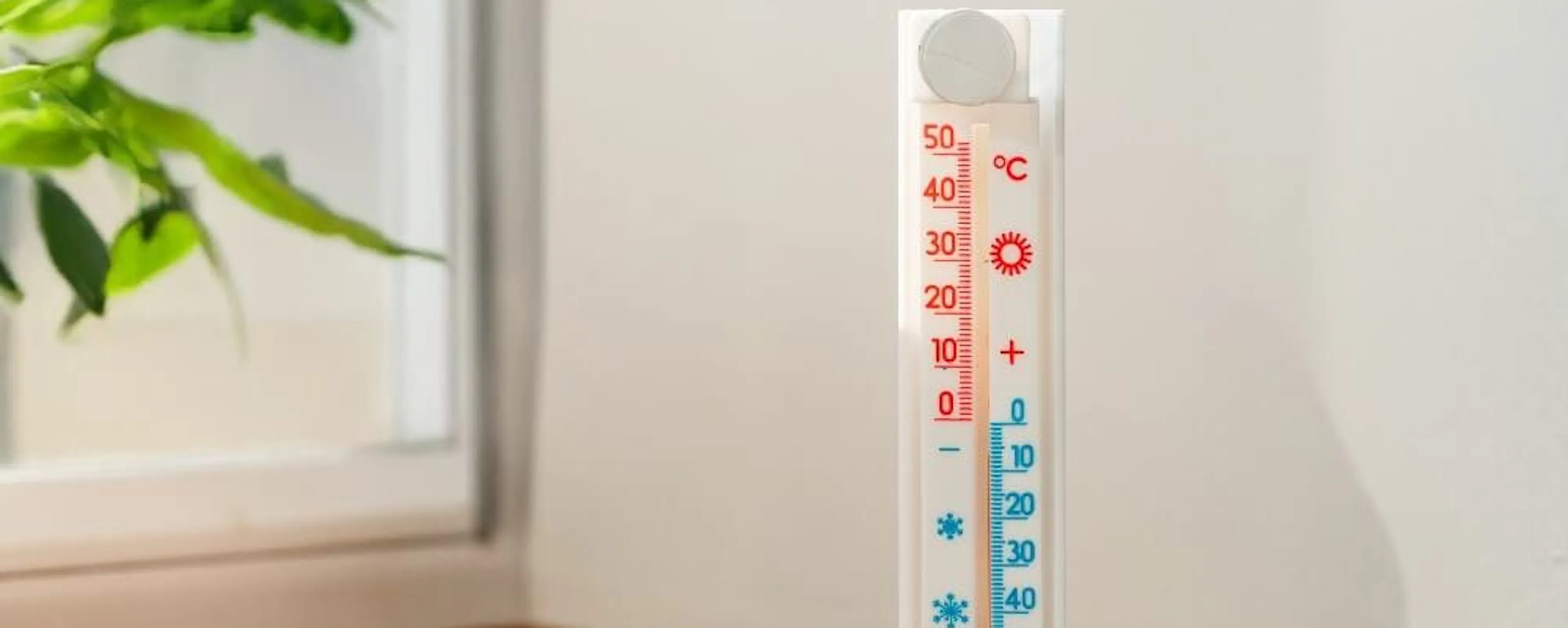 Thermomètre mural sur un rebord en bois près d'une fenêtre aidant à optimiser la capacité de chauffage