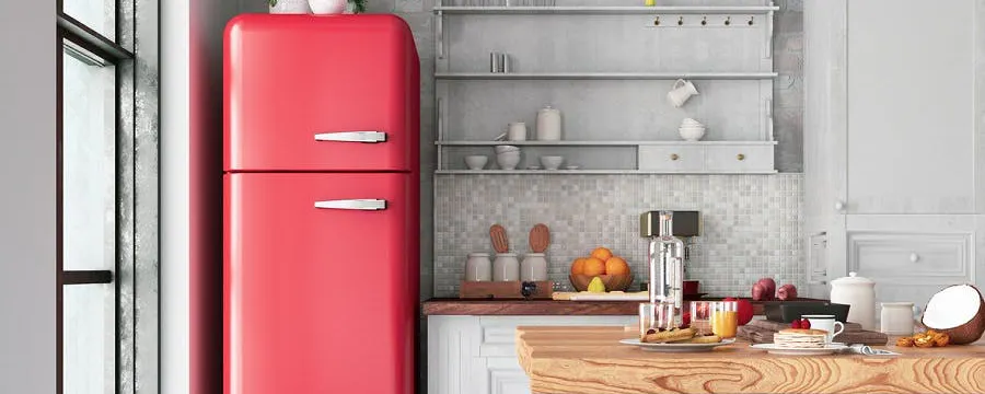 Réfrigérateur rouge vintage qui fait du bruit dans une cuisine moderne blanche