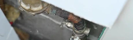 Main fermant une vanne d'arrivée d'eau avec une pince