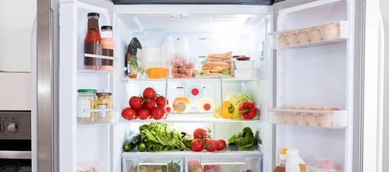 Réfrigérateur ouvert bien rempli de légumes et aliments frais