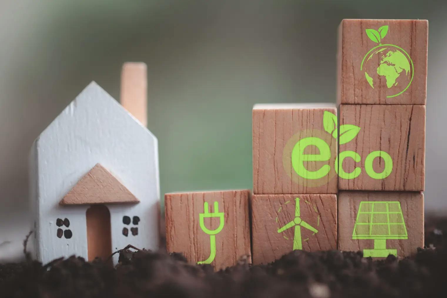 Cubes en bois avec icônes écologiques et maison miniature sur terre