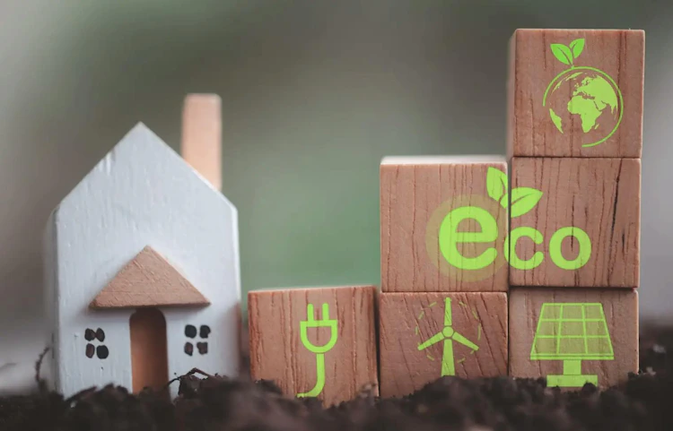 Cubes en bois avec icônes écologiques et maison miniature sur terre