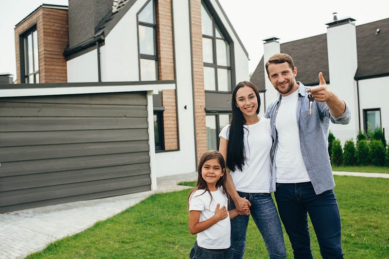 Famille souriante devant leur maison avant le départ en vacances