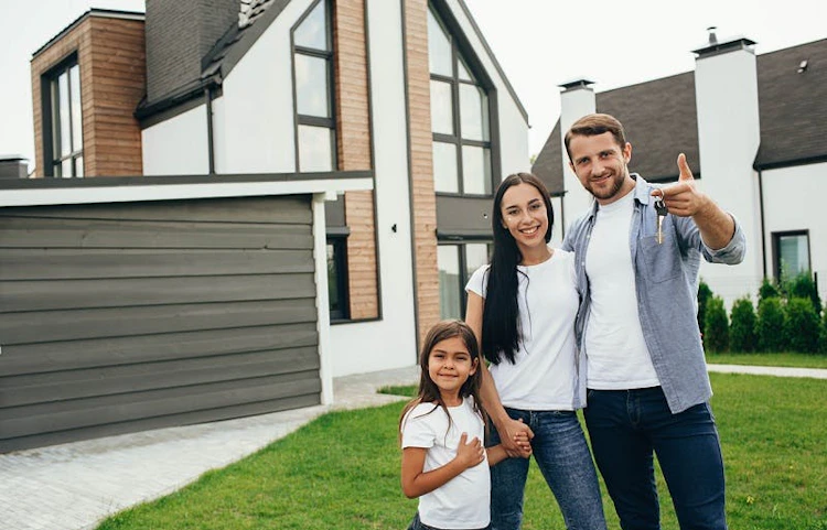 Famille souriante devant leur maison avant le départ en vacances