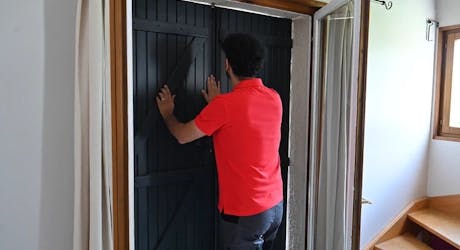 Homme vérifiant la fermeture d'une porte avant de partir en vacances