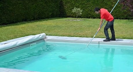 Technicien nettoyant une piscine avec une épuisette