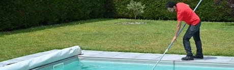 Technicien nettoyant une piscine avec une épuisette