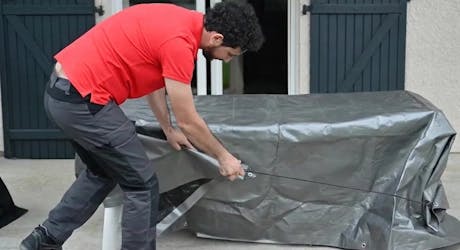 Personne recouvrant le mobilier de jardin avec une housse de protection