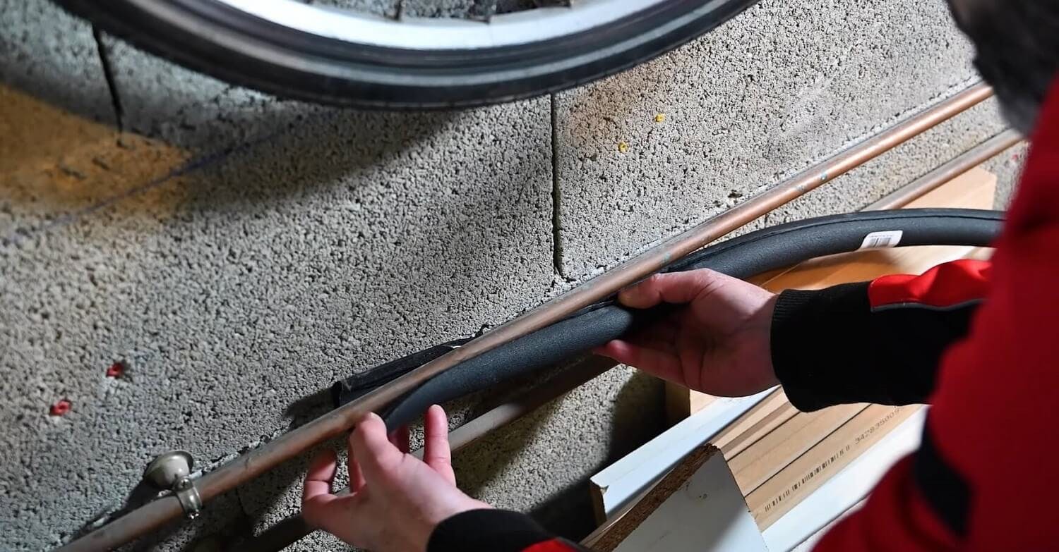 Mains posant un câble ou tuyau le long d'un mur en béton brut