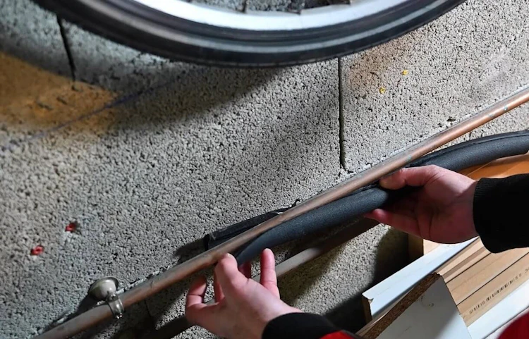 Mains posant un câble ou tuyau le long d'un mur en béton brut