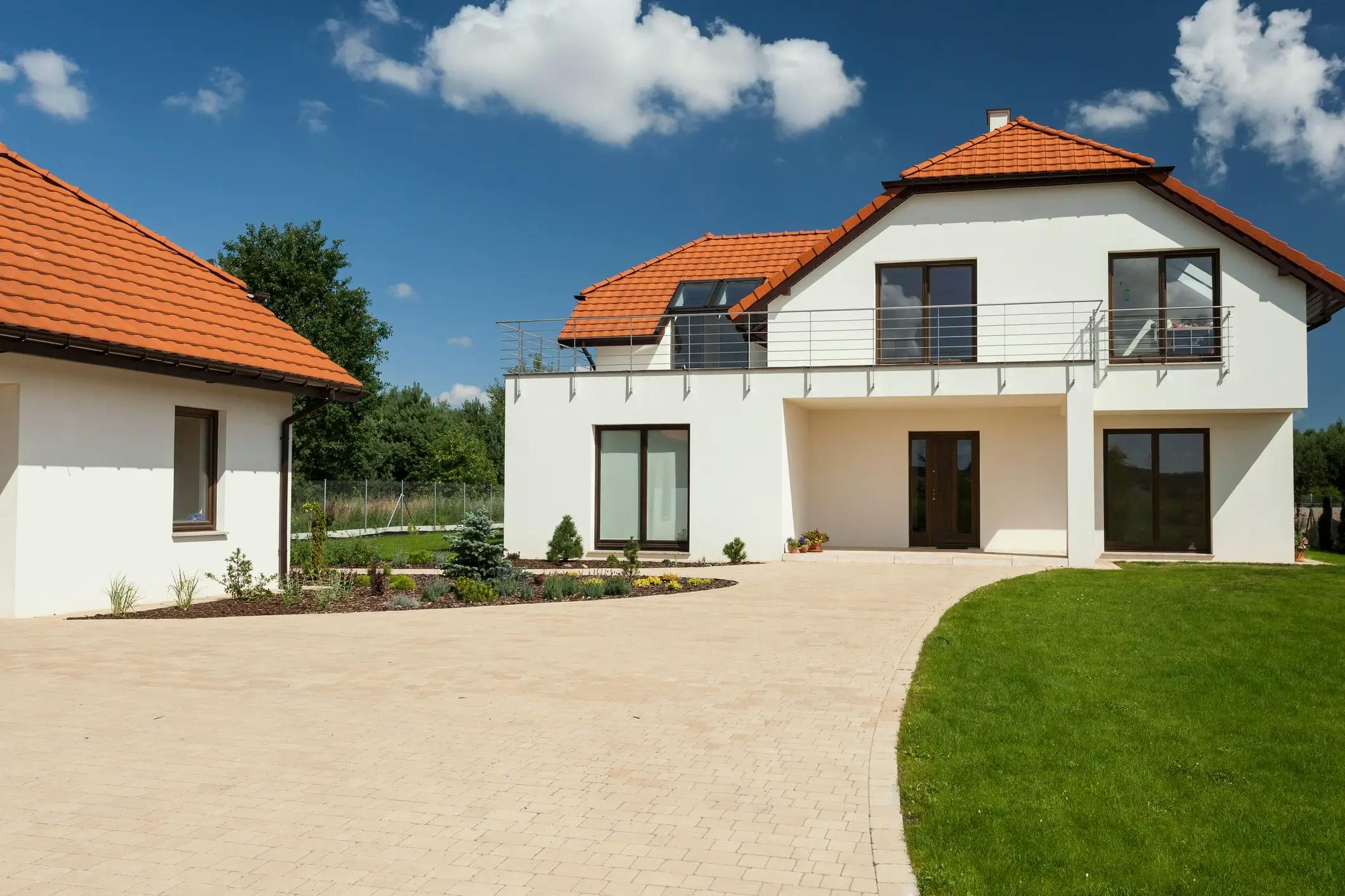 Maison individuelle blanche avec toiture en tuiles rouges et jardin
