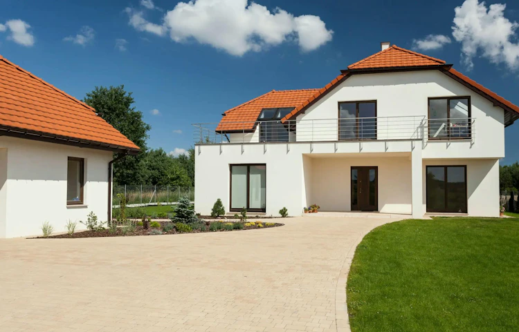 Maison individuelle blanche avec toiture en tuiles rouges et jardin