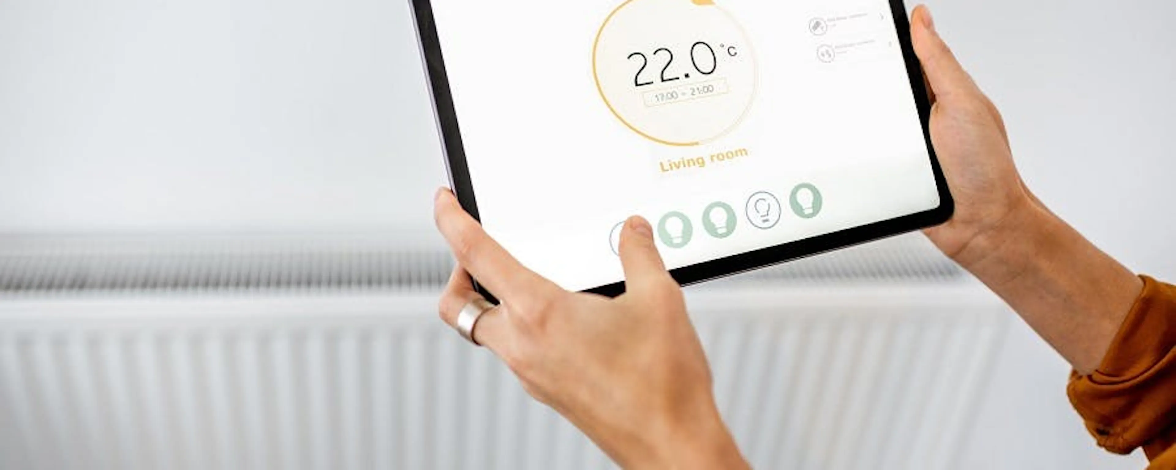 Mains tenant une tablette tactile pour radiateurs électriques connectés avec thermostat à 22°