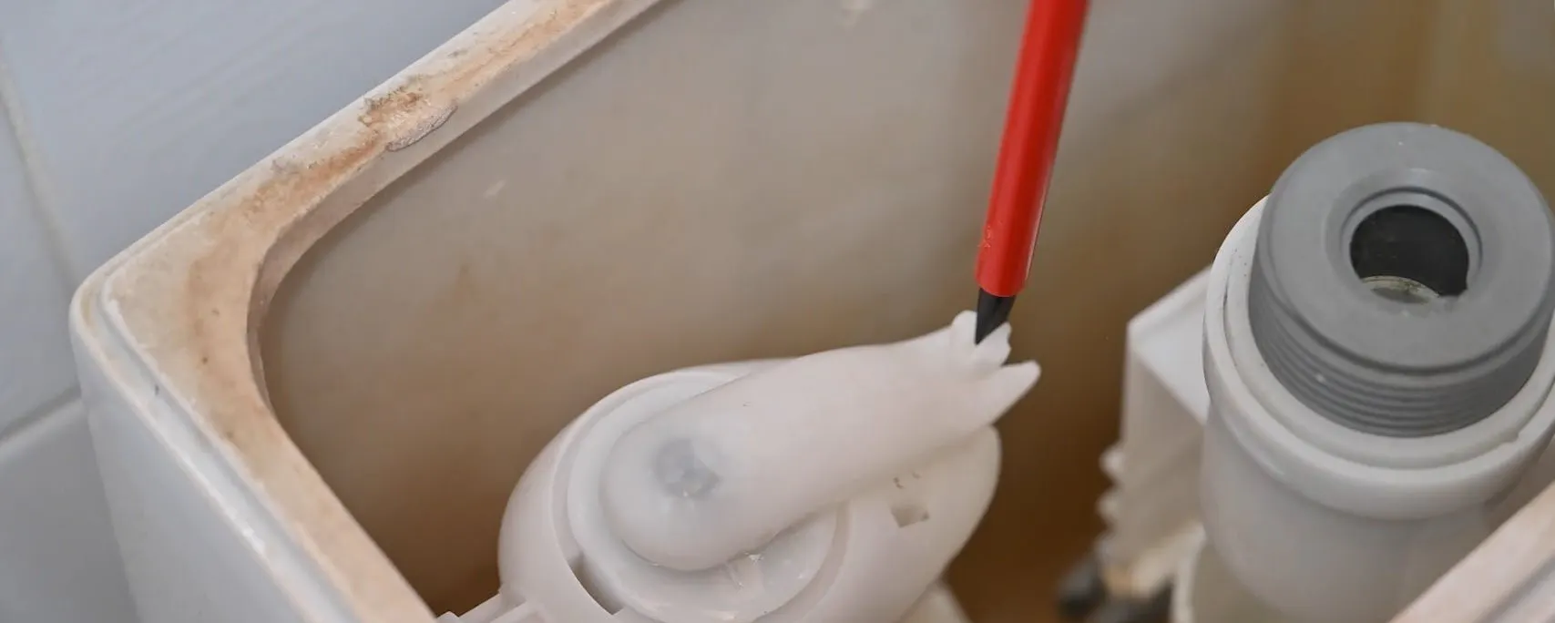 Intérieur d'un réservoir WC avec mécanisme de flotteur de chasse d'eau en train d'être réglé