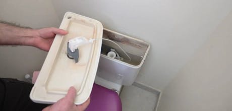 Mains soulevant le couvercle d'un réservoir de chasse d'eau