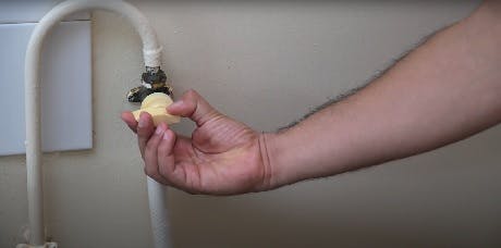 Main serrant un raccord de robinet d'arrêt avec une pièce de monnaie