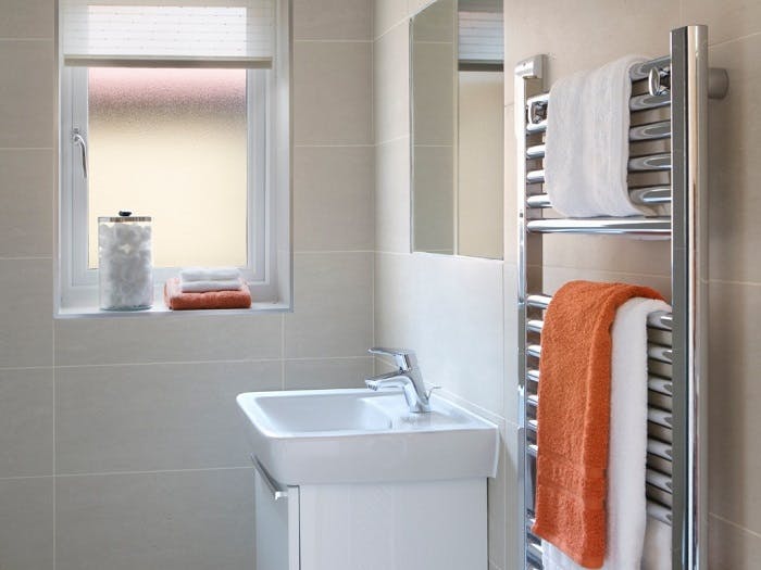 Sèche-serviette chromé avec serviettes blanches et orange dans une salle de bain moderne