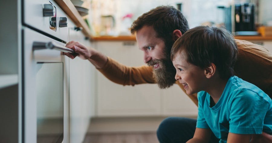 Père et enfant regardant l'intérieur d'un four de cuisine