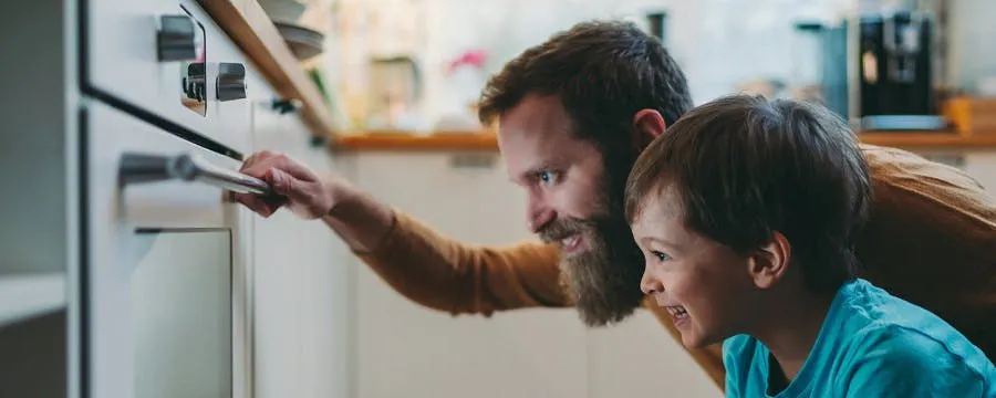 Père et enfant regardant l'intérieur d'un four afin de le réparer plutôt que les remplacer