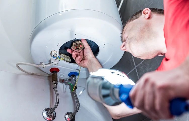 Technicien vérifiant les raccordements d'un chauffe-eau avec une clé