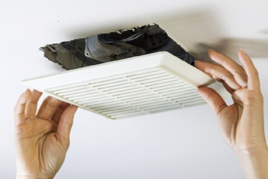 Mains installant une grille de ventilation au plafond