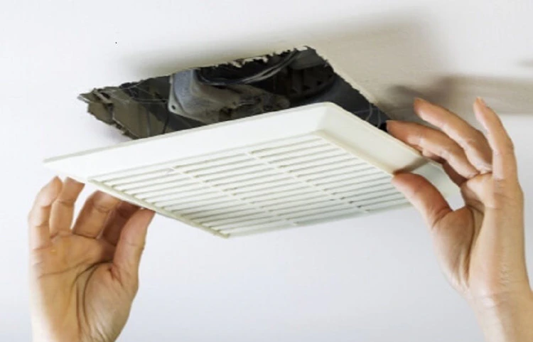 Mains installant une grille de ventilation au plafond