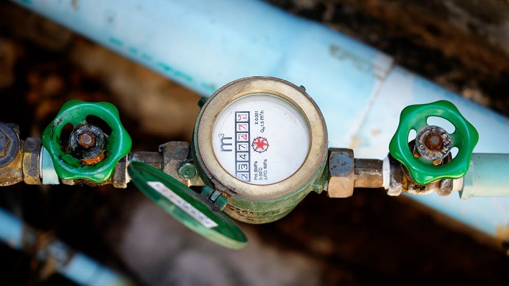 Compteur d'eau avec robinets verts sur tuyauterie bleue