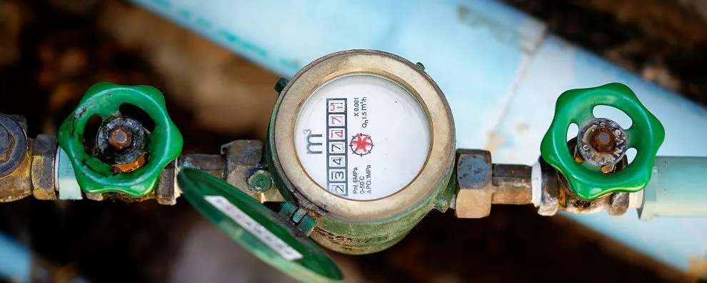 Compteur d'eau avec robinets verts sur tuyauterie bleue
