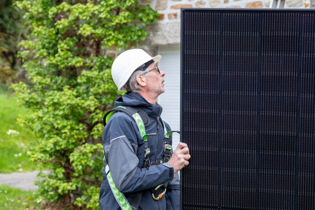 Techicien manipulant un panneau solaire sur un chantier d'installation HomeServe