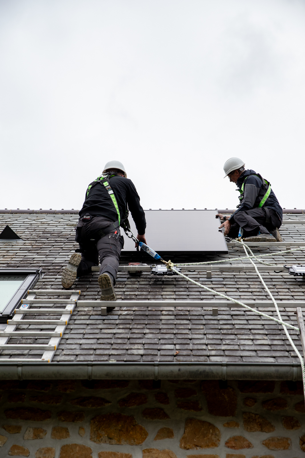 Deux techniciens HomeServe en train d'installer des panneaux solaires sur le toit d'une maison en Normandie