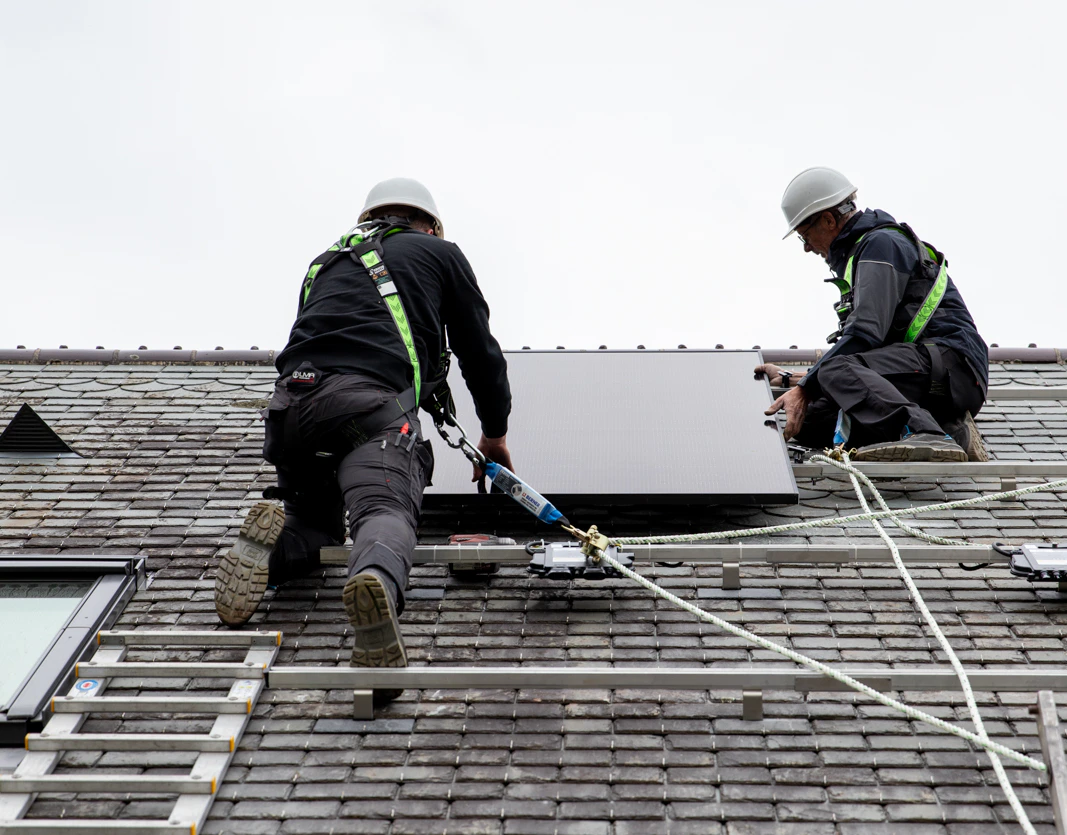 Deux techniciens HomeServe en train d'installer des panneaux solaires sur le toit d'une maison en Normandie