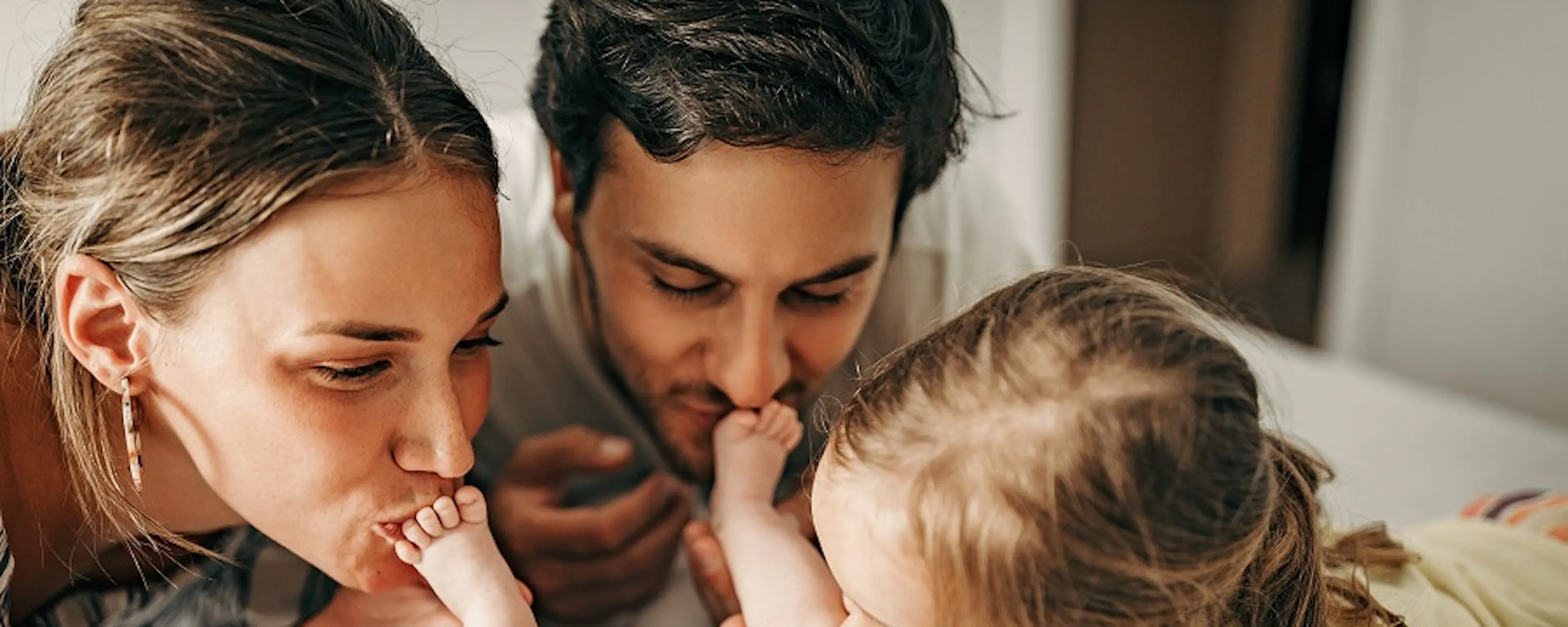 Parents et fillette embrassant tendrement un nouveau-né sur un lit