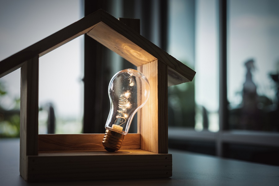 Ampoule dans une maquette de maison en bois éclairée sur bureau