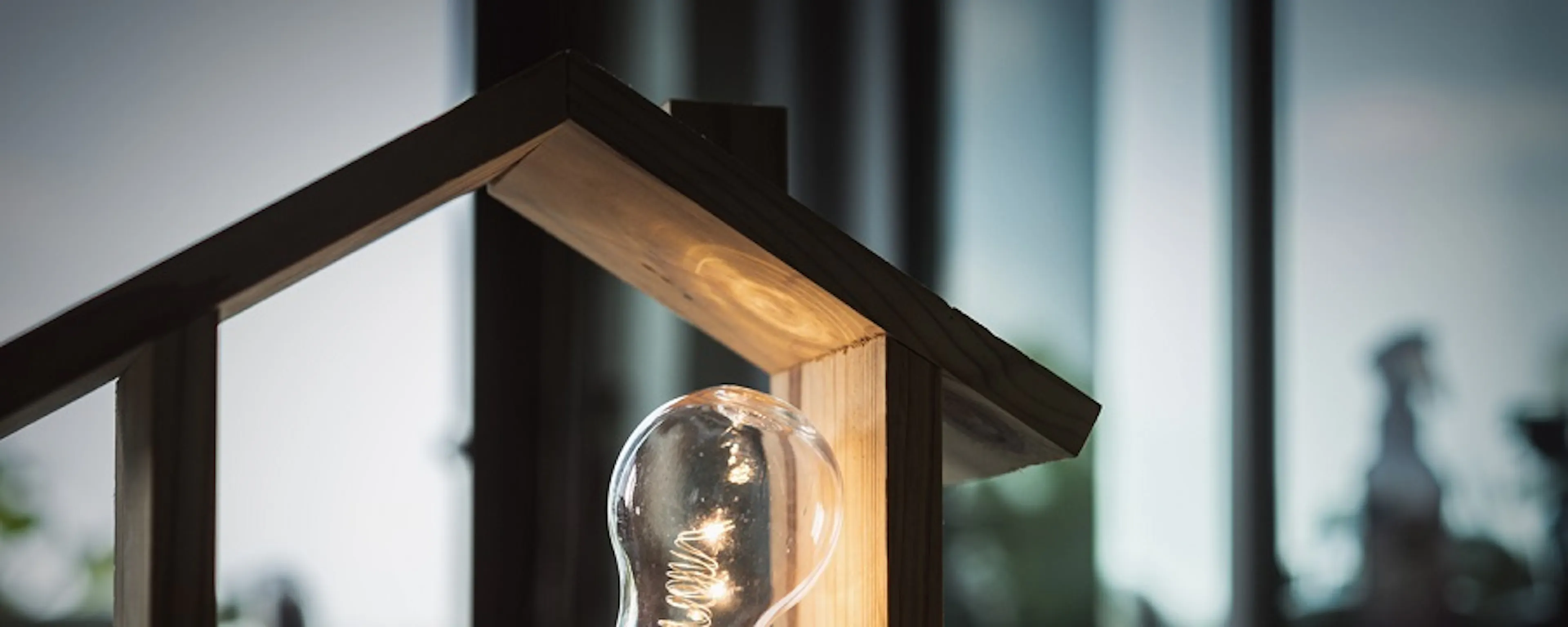 Ampoule dans une maquette de maison en bois éclairée sur bureau