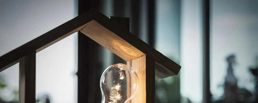 Ampoule dans une maquette de maison en bois éclairée sur bureau