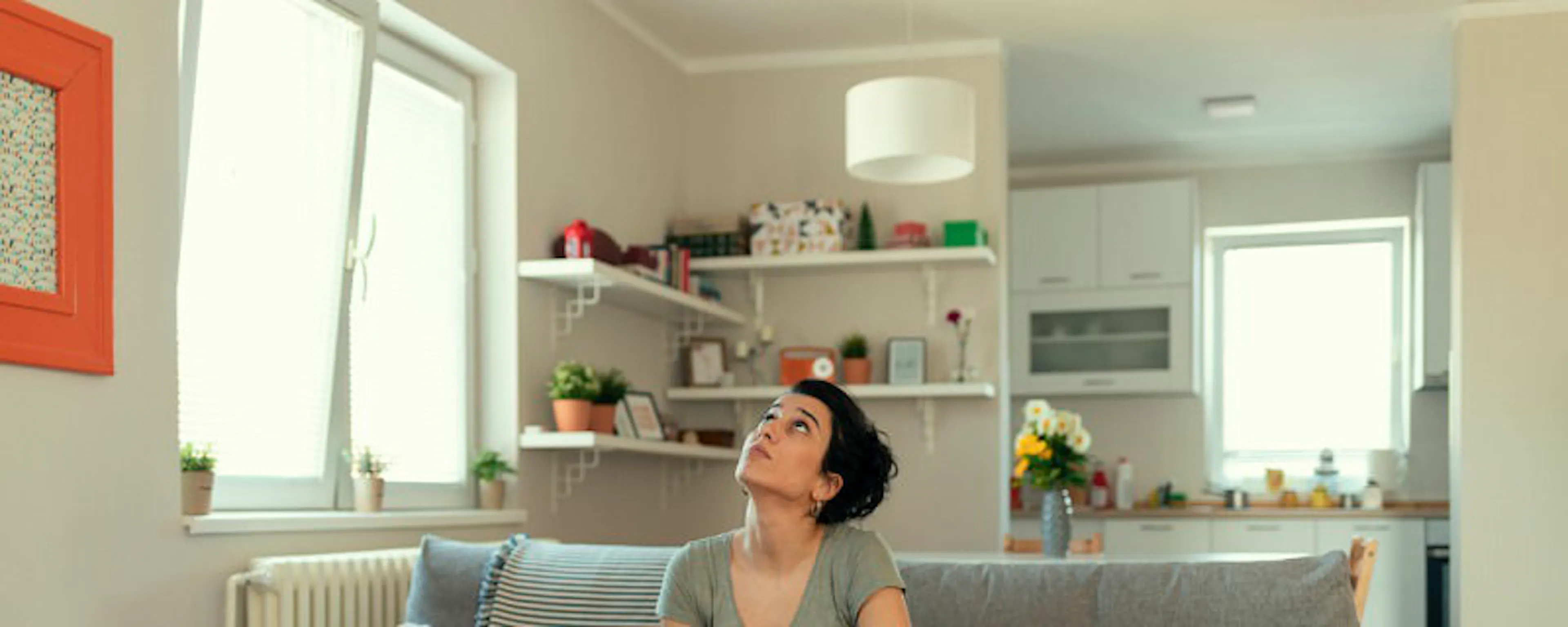 Femme assise sur un canapé avec des seaux recueillant des fuites d'eau