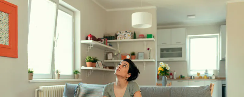 Femme assise sur un canapé avec des seaux recueillant des fuites d'eau