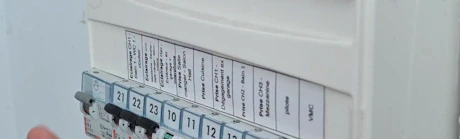 Doigt pointant un disjoncteur dans un tableau électrique numéroté