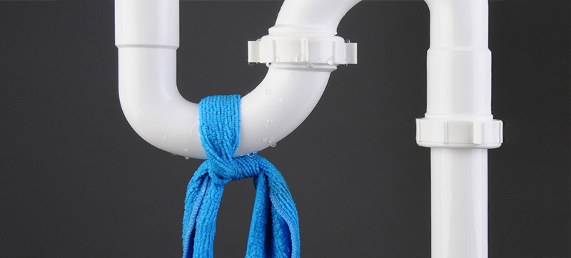 Siphon de plomberie blanc avec un chiffon bleu noué dessus