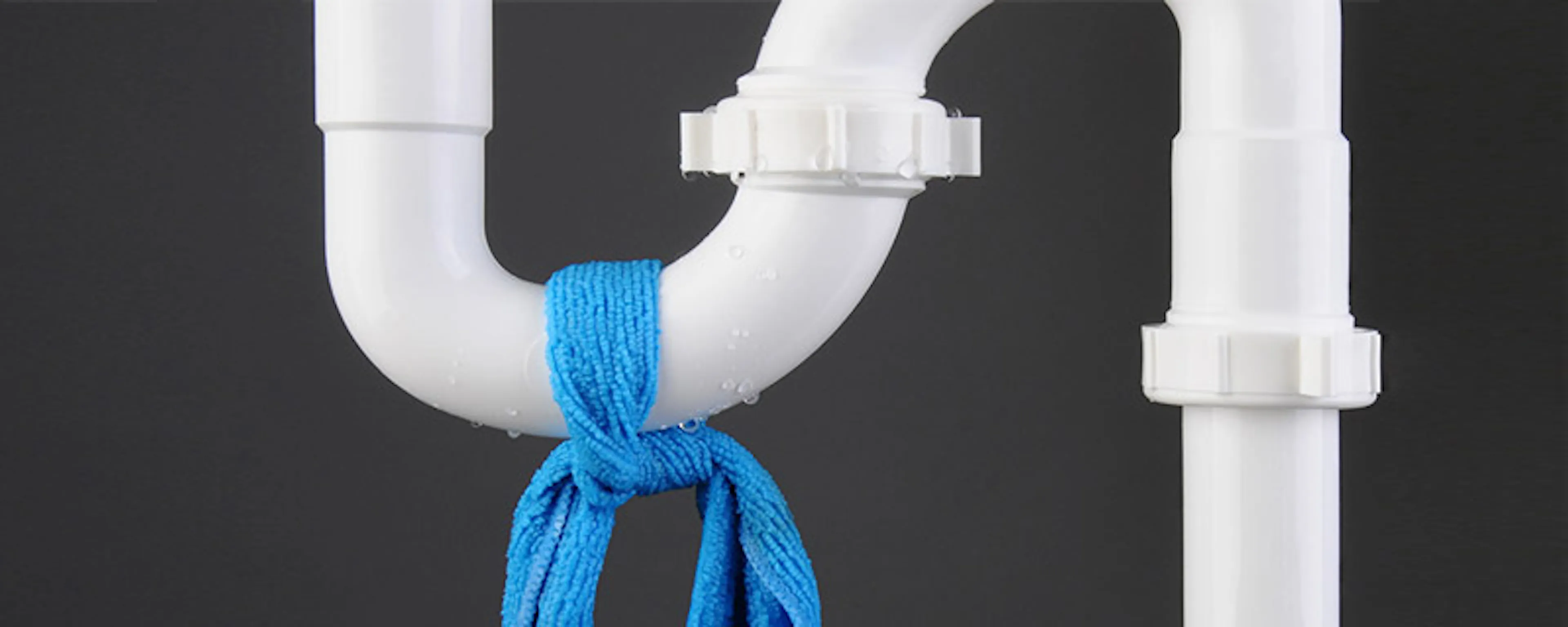 Siphon de plomberie blanc avec un chiffon bleu noué dessus