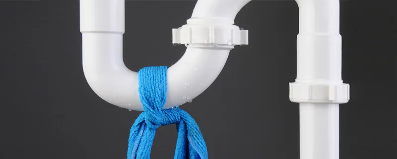 Siphon de plomberie blanc avec un chiffon bleu noué dessus