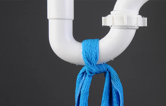 Siphon de plomberie blanc avec un chiffon bleu noué dessus