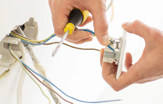Électricien connectant des fils électriques à une prise murale