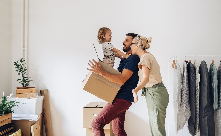 Famille joyeuse avec enfant jouant avec un carton lors d'un déménagement