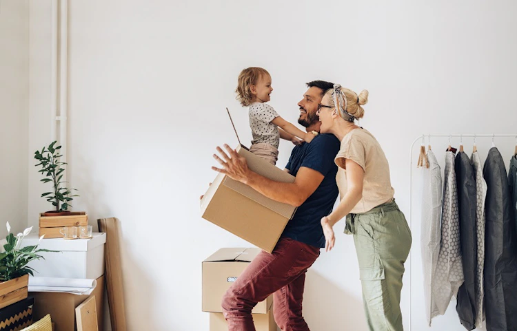 Famille joyeuse avec enfant jouant avec un carton lors d'un déménagement